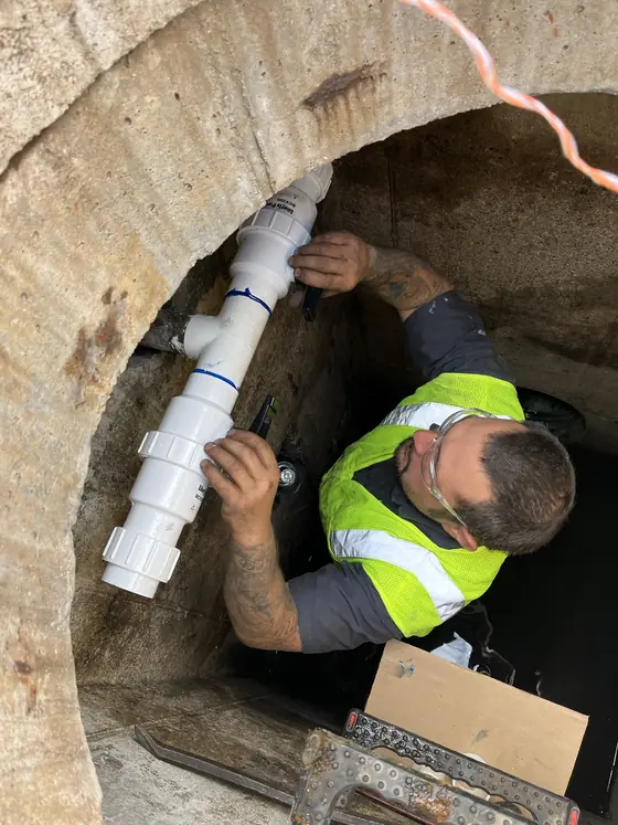 Technician working along an opened floor channel in a commercial workspace