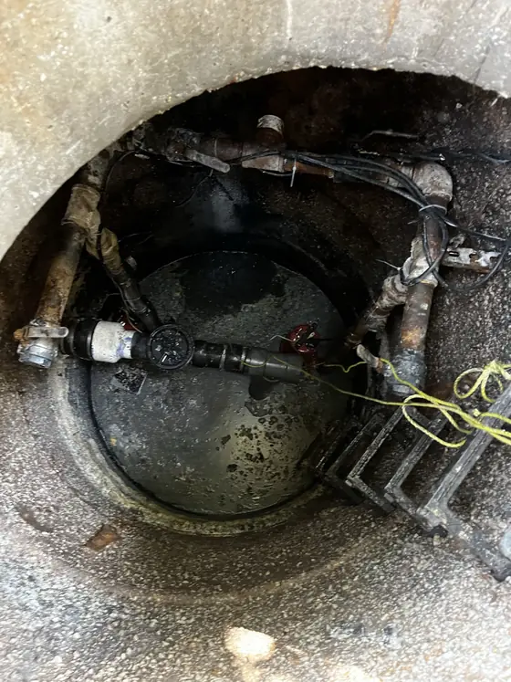 Open underground service chamber with access ladder and equipment